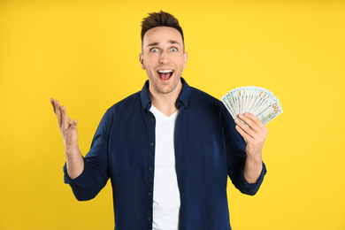 Emotional man with cash money on yellow background