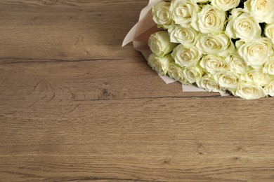Photo of Luxury bouquet of fresh roses on wooden table, space for text