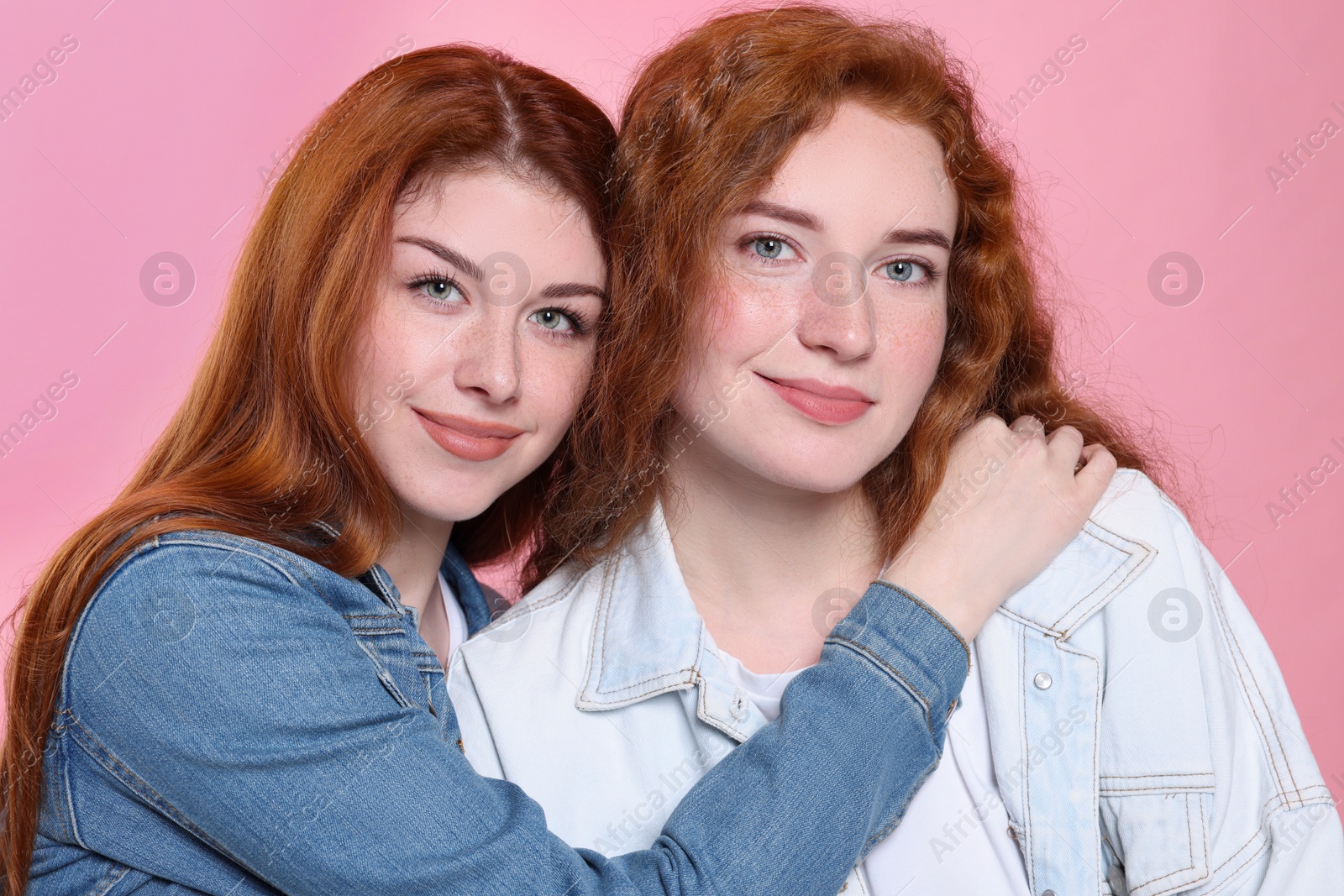 Photo of Portrait of beautiful young redhead sisters on pink background