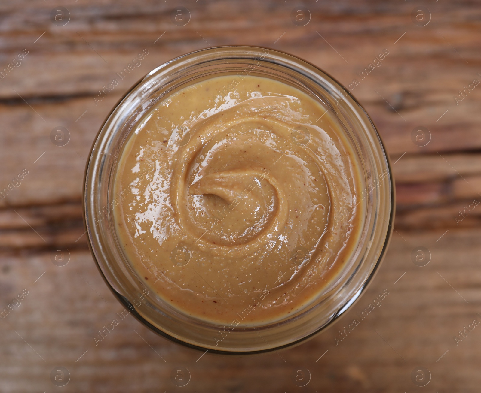 Photo of Tasty nut paste in jar on table, top view