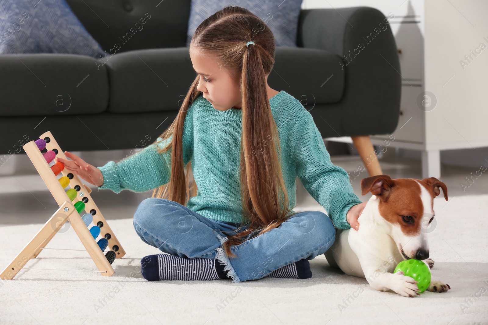 Photo of Cute girl playing with her dog on floor at home. Adorable pet