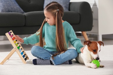 Photo of Cute girl playing with her dog on floor at home. Adorable pet