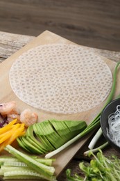 Photo of Rice paper and other ingredients for spring rolls on wooden table