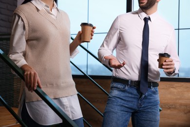 Coworkers with paper cups of coffee during break in office, closeup