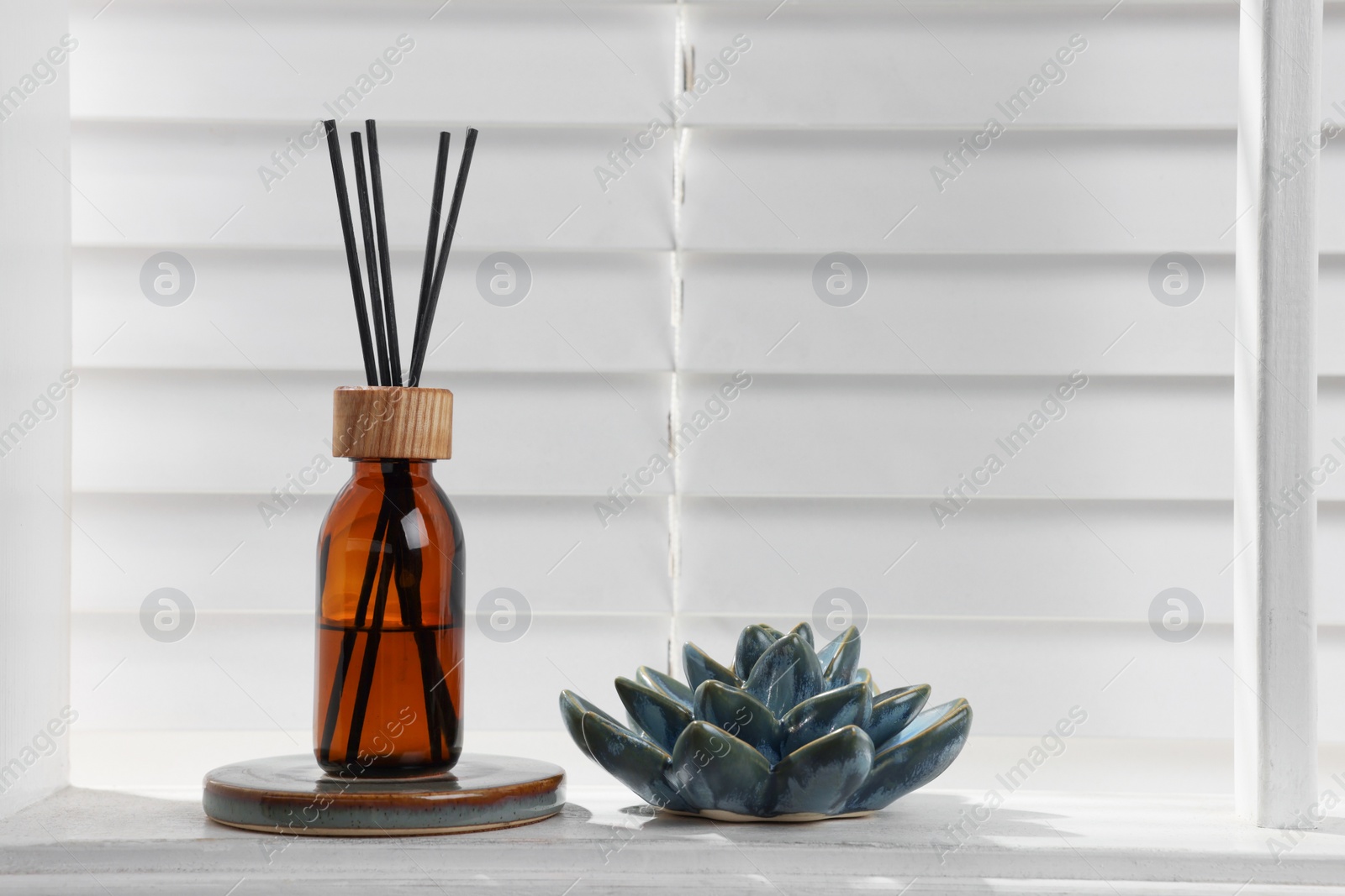 Photo of Air reed freshener and ceramic decor on white table near window. Space for text