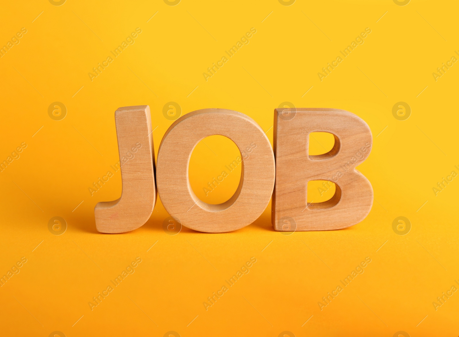Photo of Word JOB made with wooden letters on yellow background, closeup. Career concept