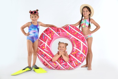 Photo of Cute little children in beachwear with bright inflatable ring on white background