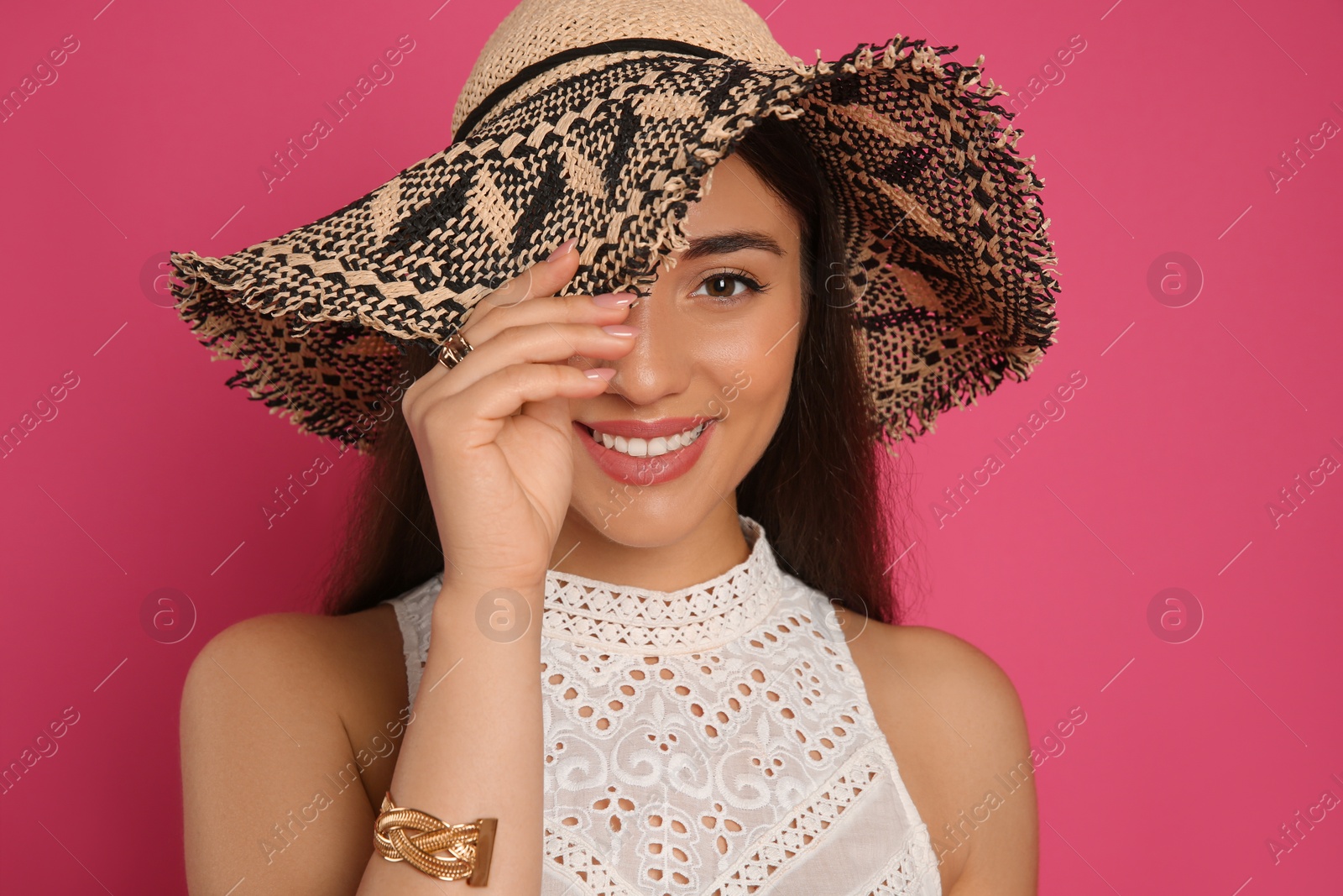 Photo of Beautiful young woman wearing straw hat on crimson background. Stylish headdress