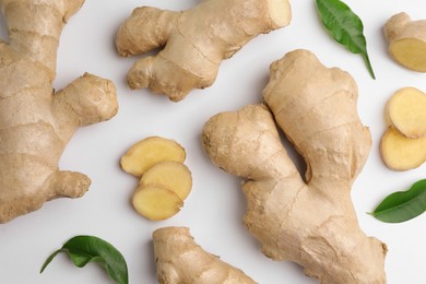 Photo of Fresh ginger with green leaves on white background, flat lay