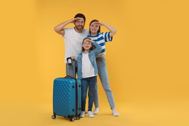 Photo of Happy family with green suitcase on orange background