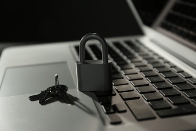 Metal lock, keys and laptop on dark background, closeup. Cyber security concept