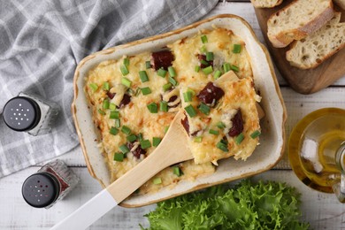 Photo of Tasty sausage casserole in baking dish served on white wooden table, flat lay