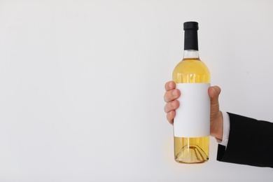 Photo of Man holding bottle of wine on light background