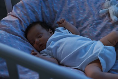 Cute newborn baby sleeping in crib at night