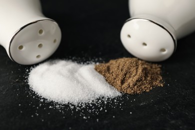 Photo of White ceramic salt and pepper shakers on black table, closeup