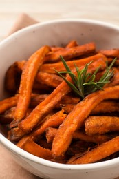Photo of Sweet tasty potato fries and rosemary in bowl, closeup