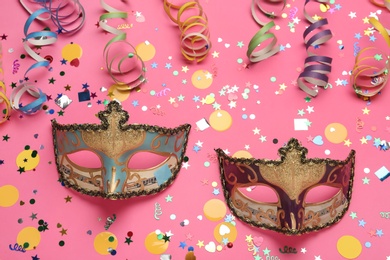 Photo of Beautiful carnival masks and party decor on pink background, flat lay