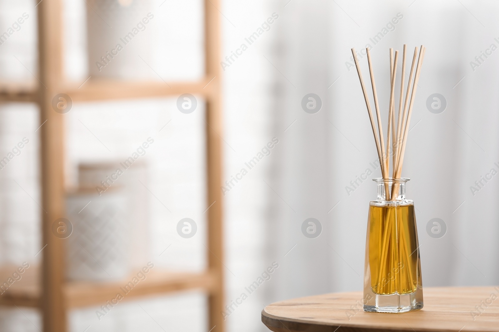 Photo of Reed air freshener on wooden table indoors, space for text