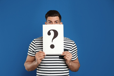 Photo of Emotional man holding question mark sign on blue background