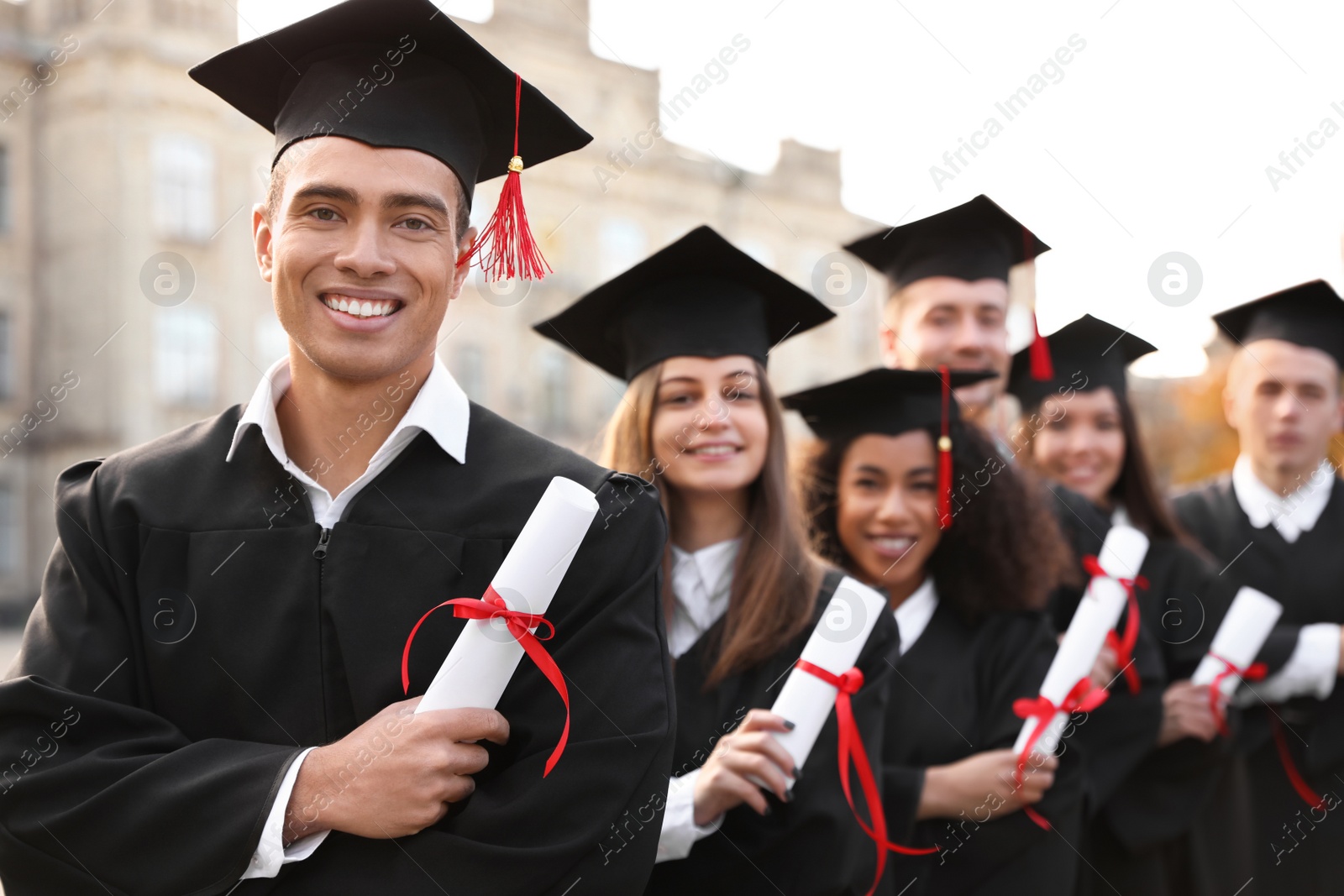 Photo of Happy students with diplomas outdoors. Graduation ceremony