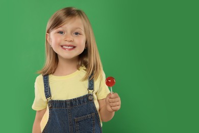 Portrait of happy girl with lollipop on green background, space for text