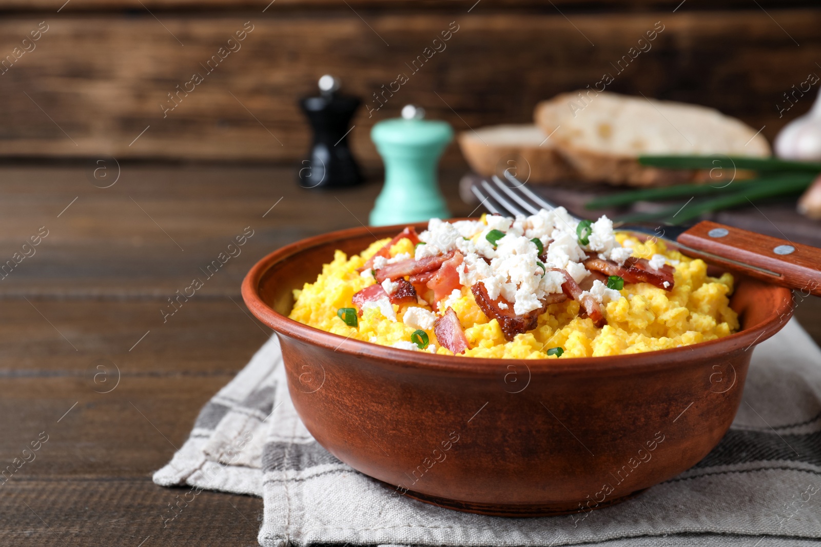 Photo of Tasty banosh served with brynza and pork cracklings in bowl on wooden table. Traditional Ukrainian dish