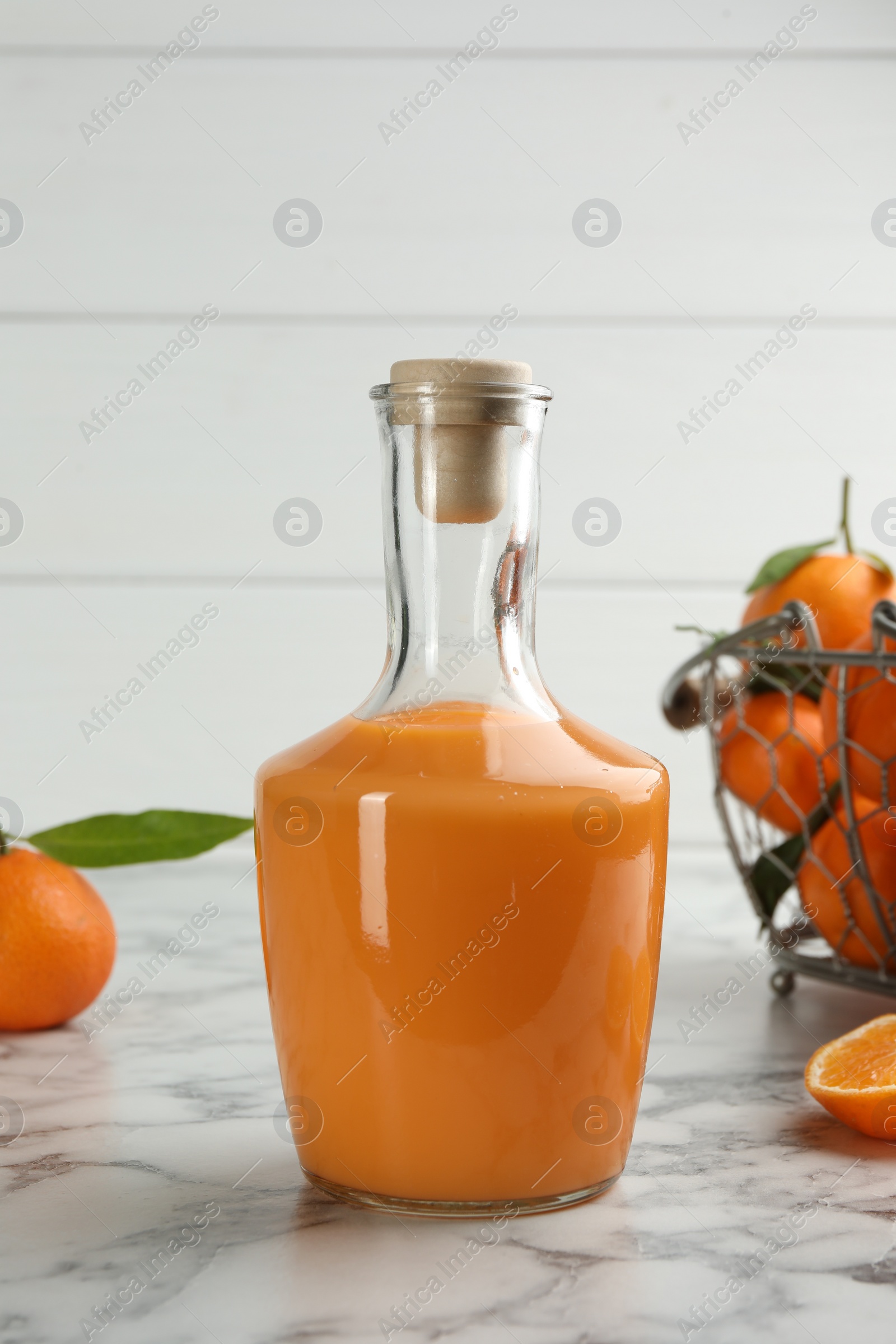 Photo of Delicious tangerine liqueur and fresh fruits on white marble table