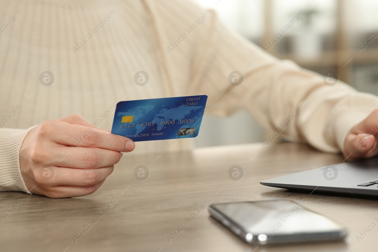 Photo of Woman with credit card using laptop for online shopping at wooden table indoors, closeup