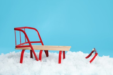 Sleigh and artificial snow on light blue background. Winter outdoor activity