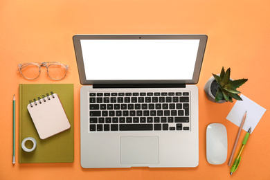 Laptop and office stationery on orange background, flat lay