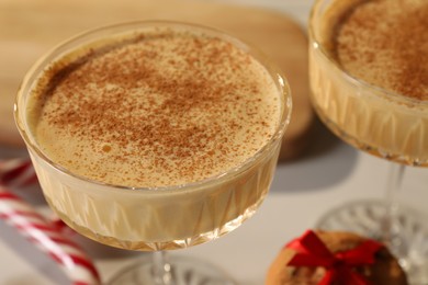 Photo of Tasty eggnog with cinnamon on white table, closeup