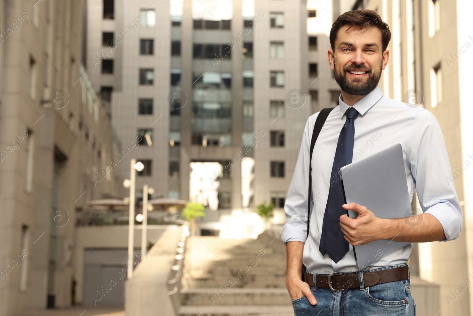 Photo of Handsome man with laptop on city street