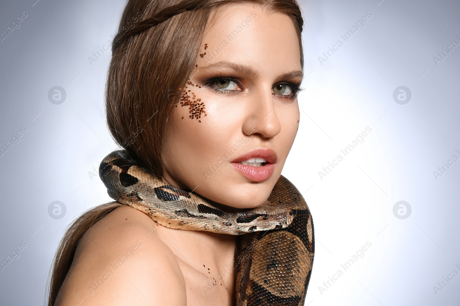Photo of Beautiful woman with boa constrictor on light grey background, closeup
