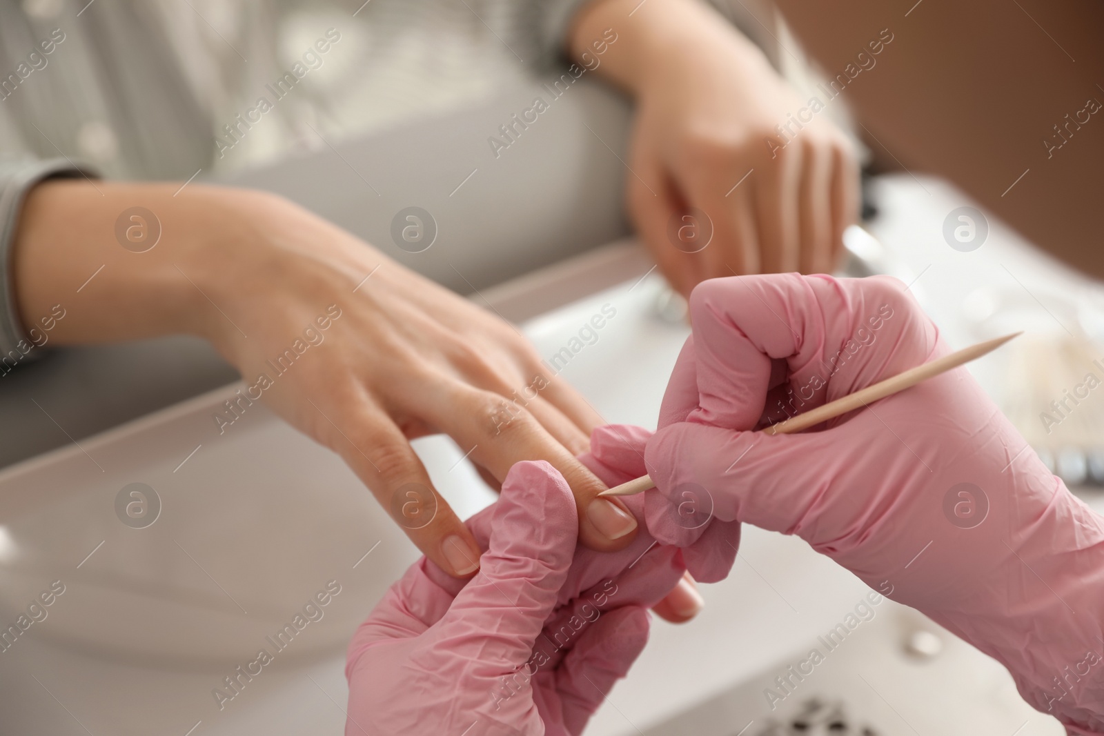 Photo of Professional manicurist working with client in beauty salon, closeup
