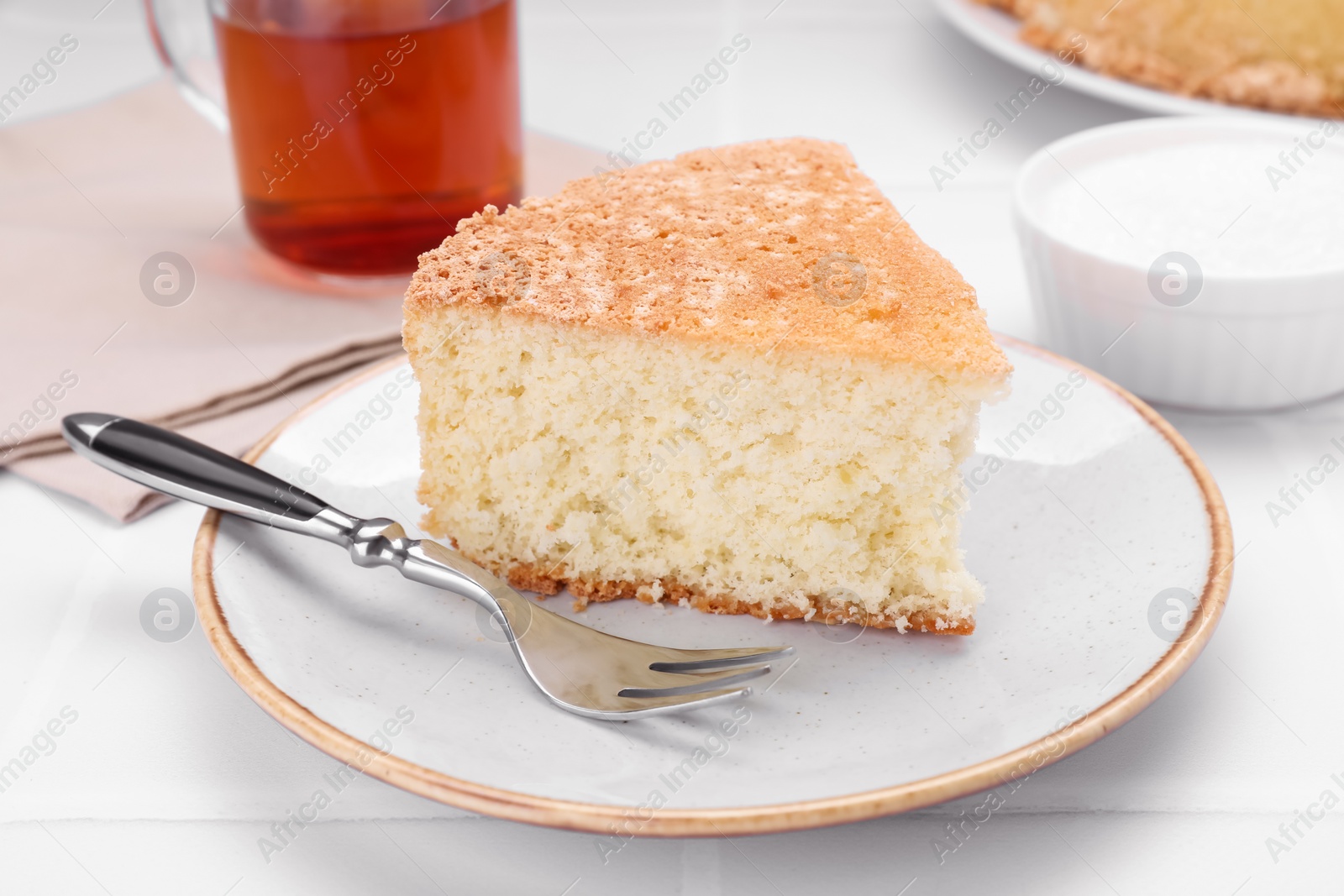 Photo of Piece of tasty sponge cake on white tiled table