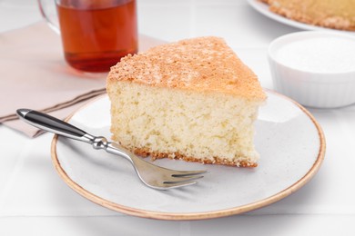 Piece of tasty sponge cake on white tiled table