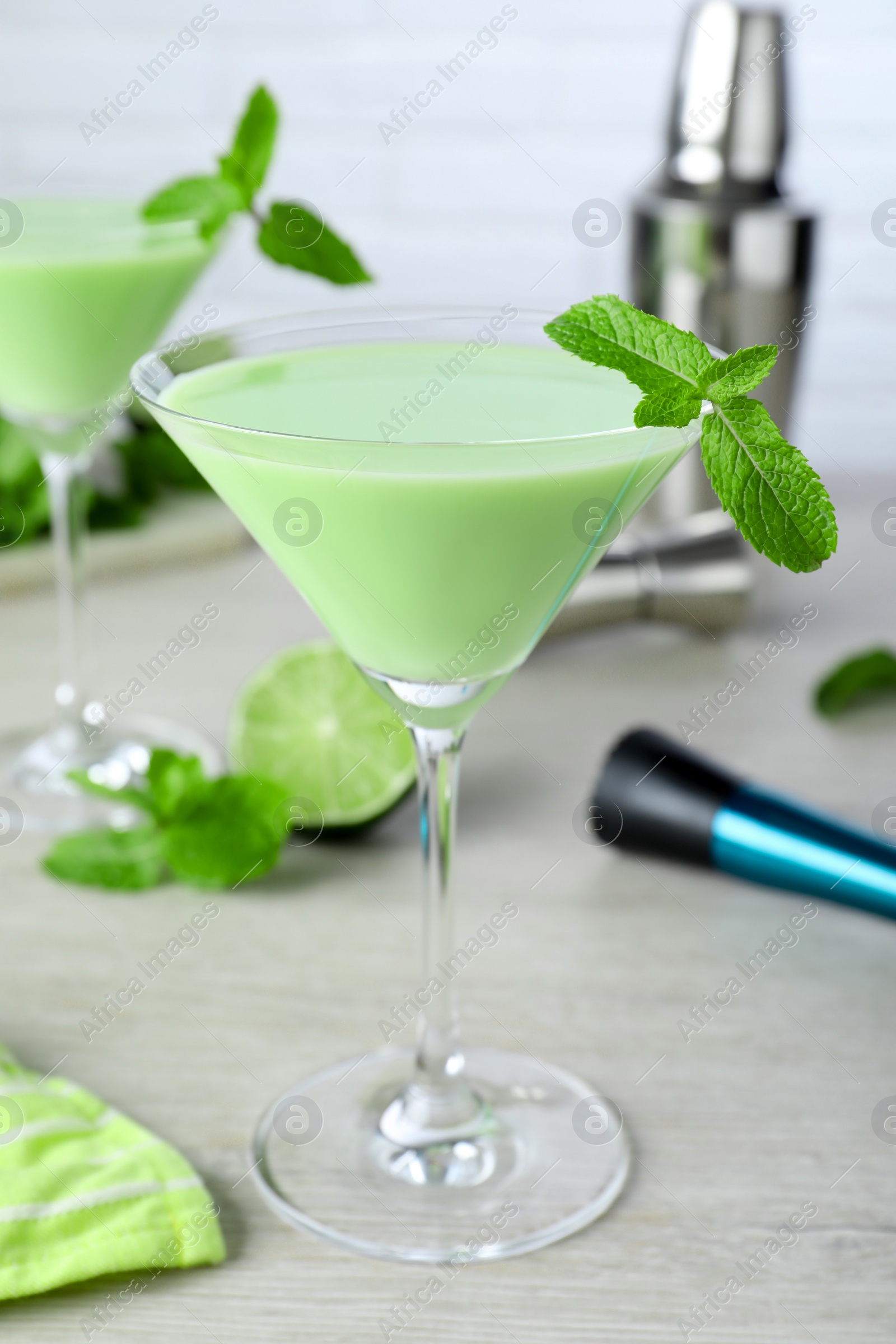 Photo of Delicious mint liqueur with green leaves on white wooden table