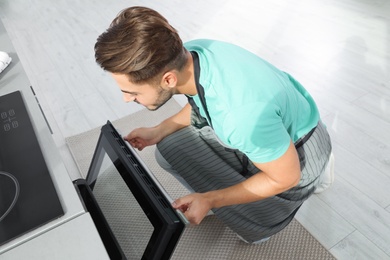 Photo of Young man baking something in oven at home