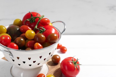 Photo of Metal colander with fresh tomatoes on white table, closeup. Space for text