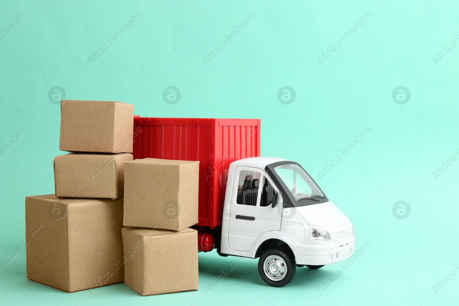 Photo of Truck model and carton boxes on turquoise background. Courier service