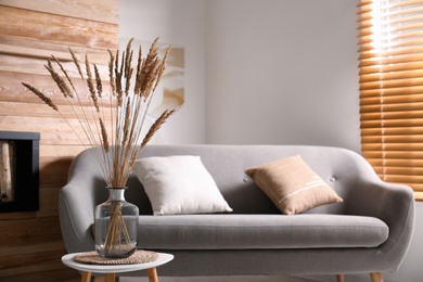 Vase with decorative dried plants on table in living room. Interior design