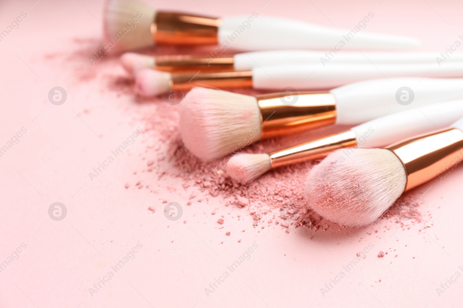 Photo of Different makeup brushes with crushed cosmetic product on pink background, closeup. Space for text