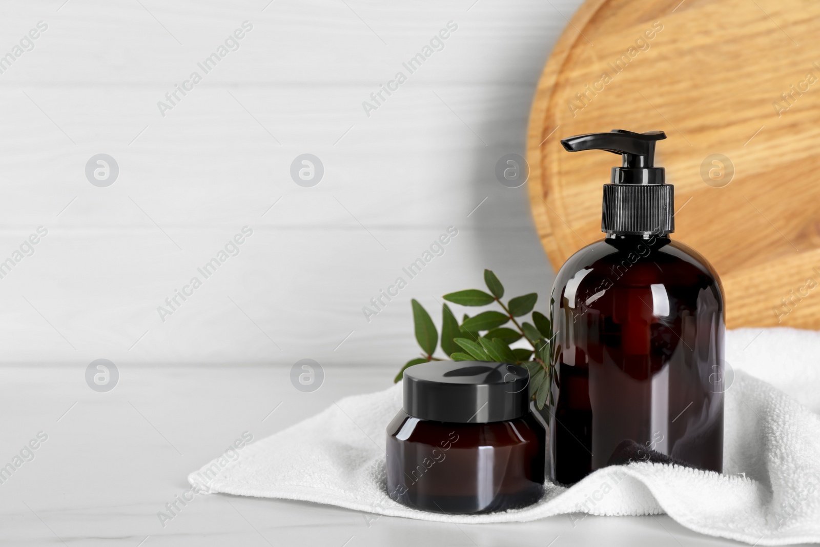 Photo of Shampoo bottle, hair mask and towel on white wooden table, space for text