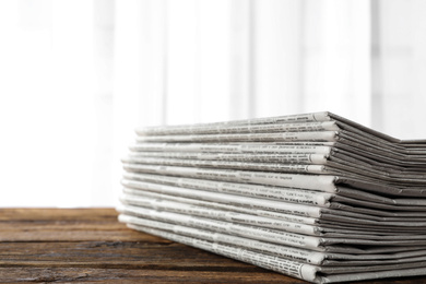 Photo of Stack of newspapers on wooden table. Journalist's work