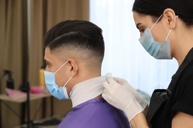 Photo of Professional stylist working with client in salon. Hairdressing services during Coronavirus quarantine