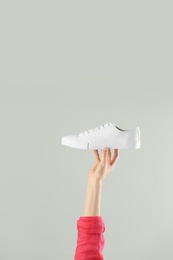 Photo of Woman holding sportive shoe on light background, closeup. Space for text