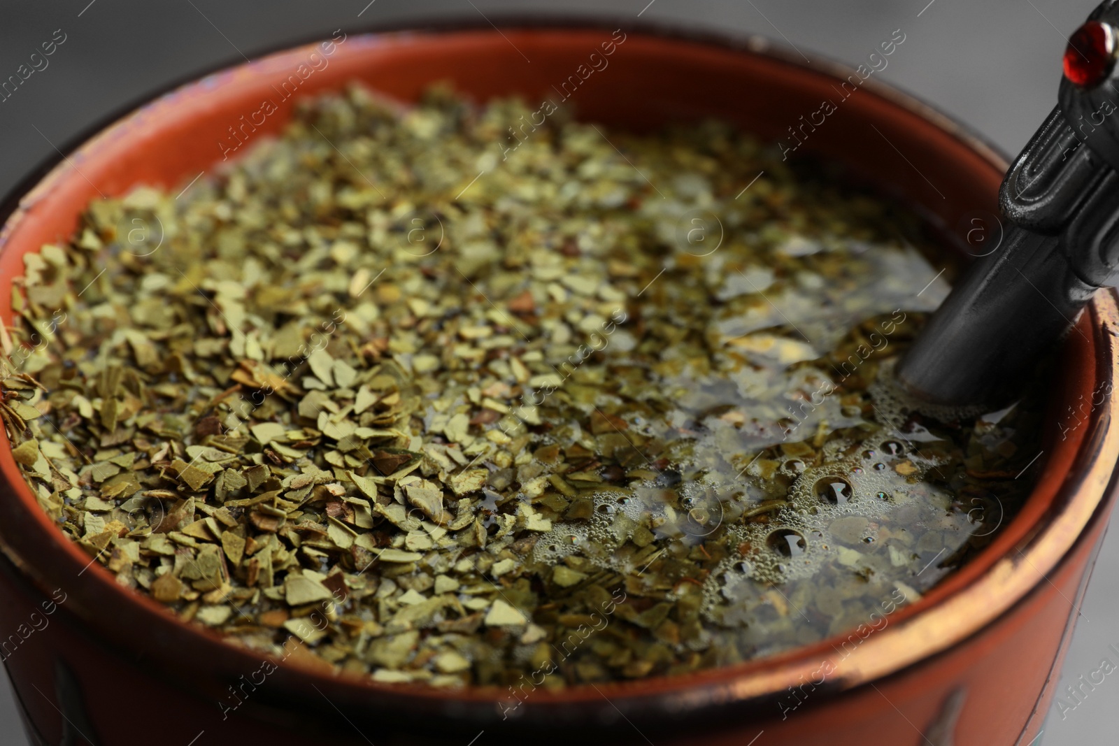 Photo of Guampa with bombilla and mate tea on grey background, closeup