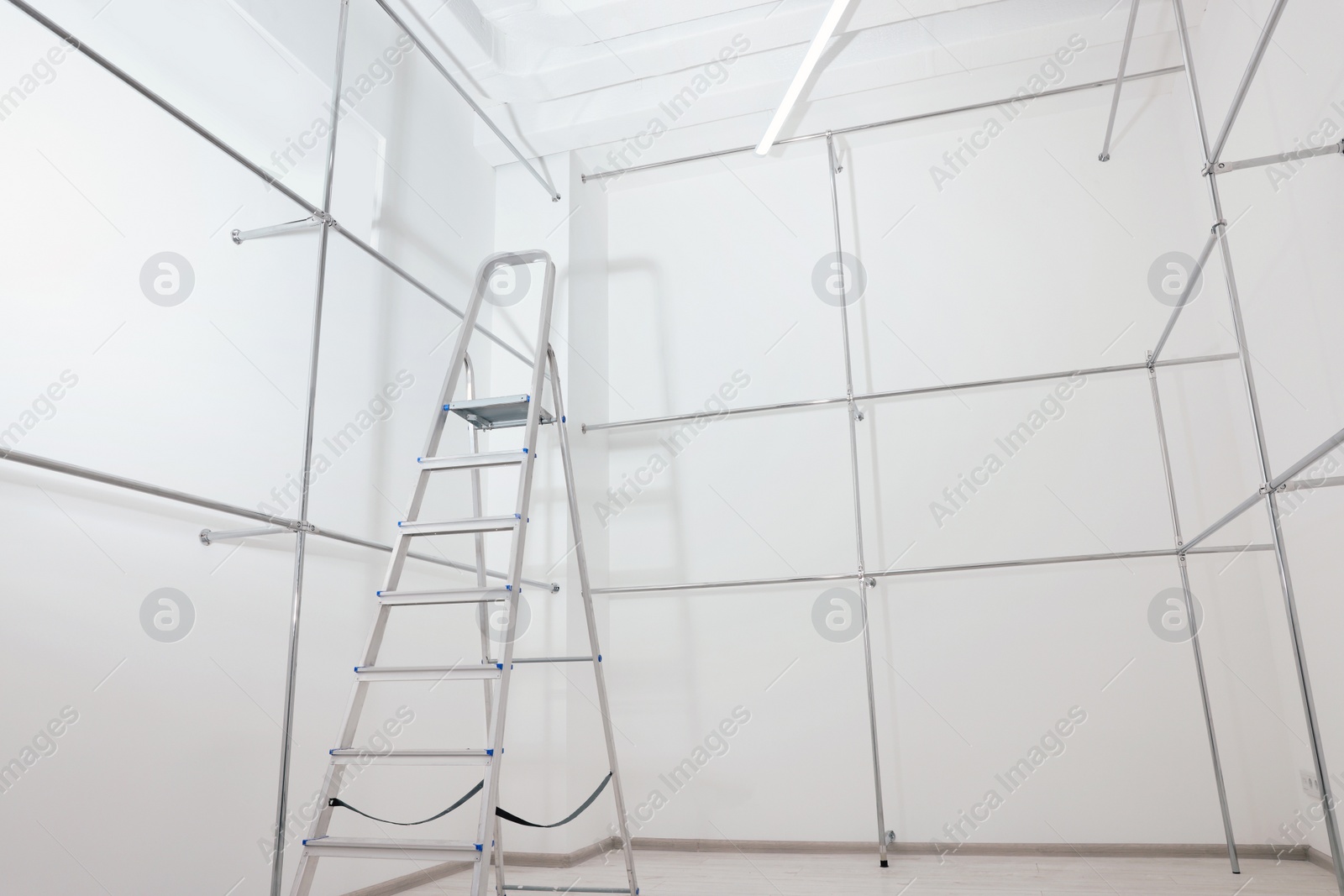 Photo of Ladder and metal pipes in empty renovated room