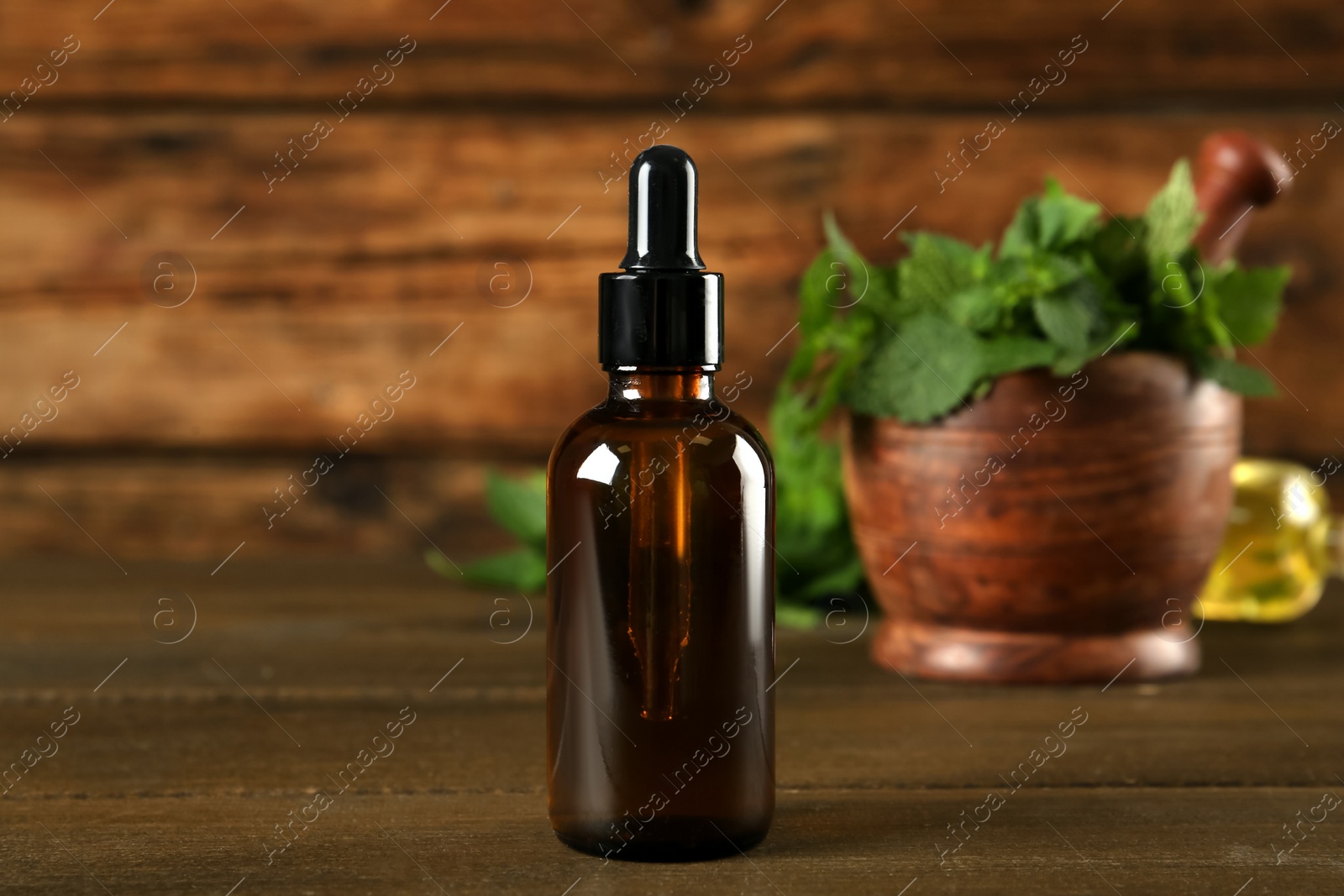 Photo of Glass bottle of nettle oil with dropper on wooden table