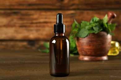 Glass bottle of nettle oil with dropper on wooden table